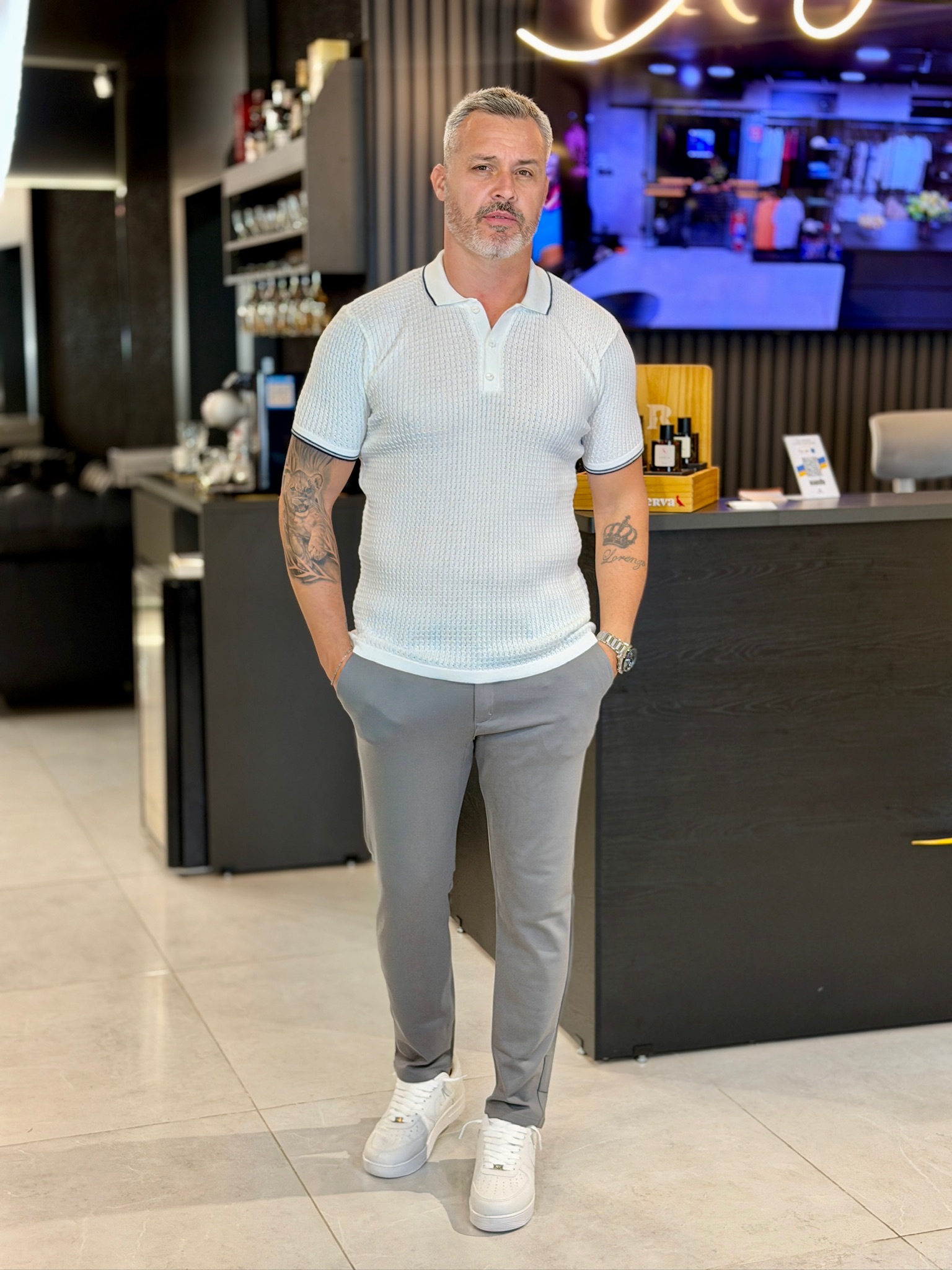Polo branco com calça cinza e tênis branco na Majestade